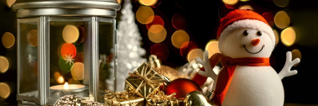 Christmas composition: A snowman, a lantern with candles, bright shiny boxes with gifts, blurred bokeh lights in the background.