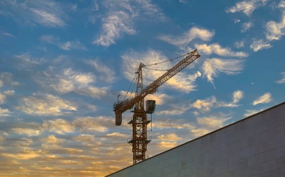 The crane in the city against the backdrop of a beautiful sky with clouds