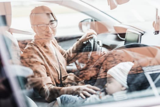 Mother concentrating on driving family car running errands while her baby sleeps in infant car seat by her site