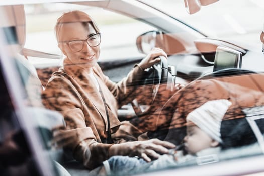 Mother driving family car, running errands, while her baby sleeps in infant car seat by her site