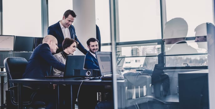 Workplace in modern office with business people brainstorming. Businessman working on laptop during the meeting.