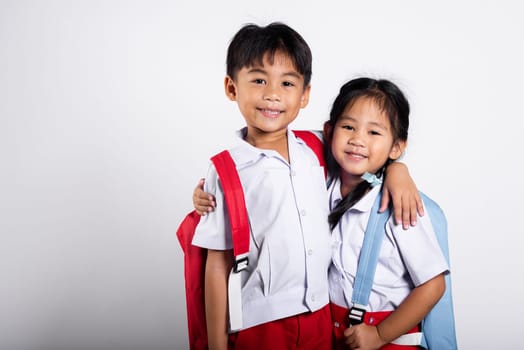 Two Asian student kid girl boy schoolchildren brother sister smile happy wear student thai uniform red pants skirt hug each other isolated on white background, Portrait little children girl preschool