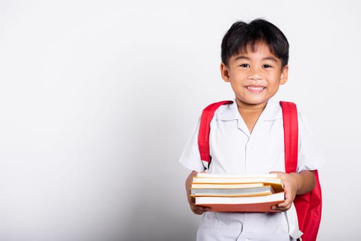 Asian adorable toddler smiling happy wearing student thai uniform red pants stand books for study ready for school isolated on white background, Portrait little children boy preschool, Back to school