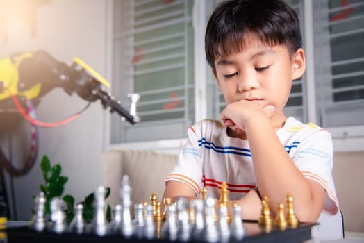 Asian little boy thinking and wait robot arm playing chess, STEM education E-learning, Funny children learning successful getting a lesson control robot arm game, Technology science education concept