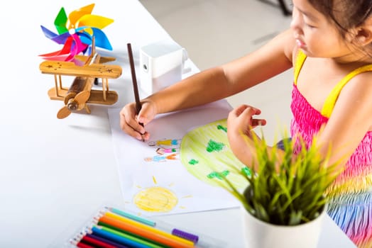 Asian cute kid preschooler sit on table smiling she draw picture with pencil at home, Happy child little girl colorful drawing family standing hold hands on planet earth on paper, earth day concept