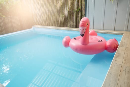Pink inflatable ring flamingo plastic in the swimming pool blue water, Pool accessory equipment float for party, Trendy summer vacation feeling concept