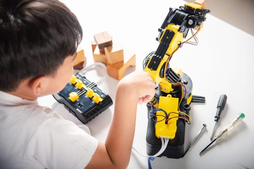 Happy Asian little kid boy using screwdriver to fixes screws robotic machine arm in home workshop, child learning repairing get lesson control robot arm, Technology future science education concept