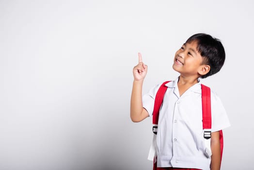 Asian toddler smiling happy wear student thai uniform red pants keeps pointing finger at copy space in studio shot isolated on white background, Portrait little children boy preschool, Back to school