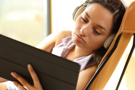 Bored woman watching videos on tablet sitting at home