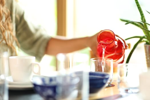Close up portrait of a woman hand filling glass with water from bottle in a restaurant