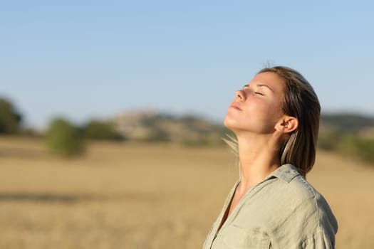 Beautiful woman breathing fresh air in a rural field