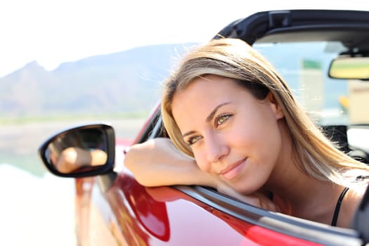 Portrait of a happy convertible car driver looking away