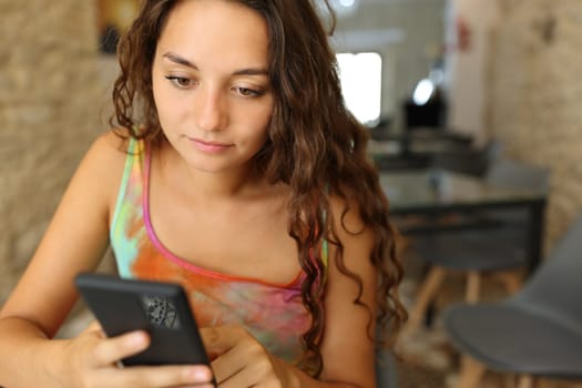 Serious woman using smart phone sitting in a restaurant