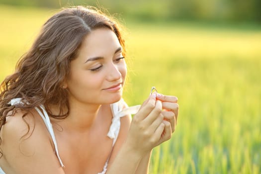 Happy woman looking at her engagement ring sitting in a field