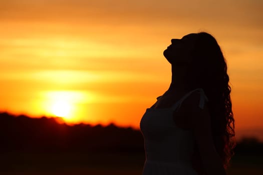 Side view portrait of a woman silhouette breathing fresh air at sunset or sunrise