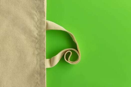 Fabric cotton shopping bag on a green background. Zero waste and ecological concept. Top view, copy space.