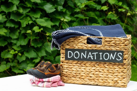 Donation box for clothing donations on a greenery background. Charity and donation concept, copy space.