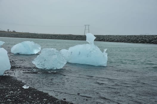 Crystal clear ice chunks at Diamond beach with black sand in Fellsfjara, Jokulsarlon on Iceland