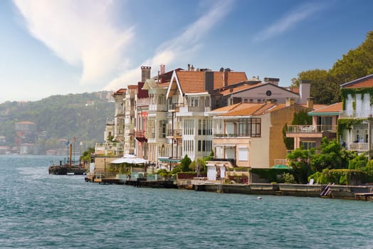View from the sea of the European side of Bosphorus strait, Istanbul, Turkey, with traditional houses, and background of green mountains with dense trees, in a summer day