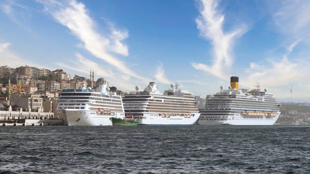 Three huge cruise ships docked at terminal of Galataport, located along shore of Bosphorus strait, in Karakoy neighbourhood, with Galata tower in the background, Istanbul, Turkey