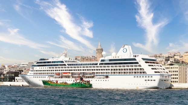 Huge cruise ship docked at terminal of Galataport, located along shore of Bosphorus strait, in Karakoy neighbourhood, with Galata tower in the background, Istanbul, Turkey