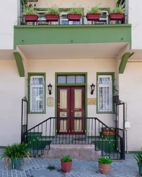 Exterior facade of old colorful residential building with door, wrought iron windows and flowerpots, in a cobblestone alley, suited in Anadolu Kavagi district, Istanbul, Turkey, in a summer day
