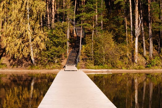 Wooden pier and wooden staircase on the lake Baltieji Lakajai in Labanoras Regional Park in autumn, Picturesque nature of Lithuania.