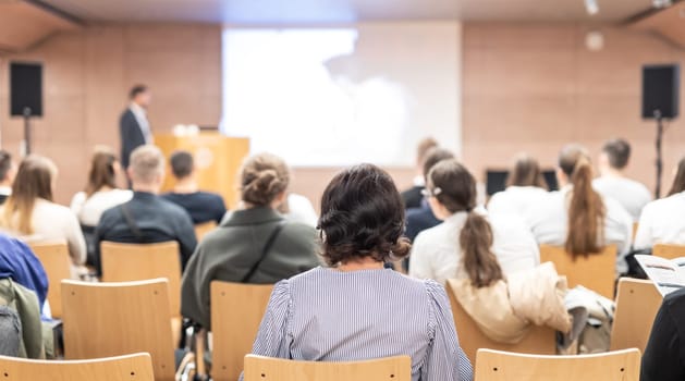 Speaker giving a talk in conference hall at business event. Rear view of unrecognizable people in audience at the conference hall. Business and entrepreneurship concept