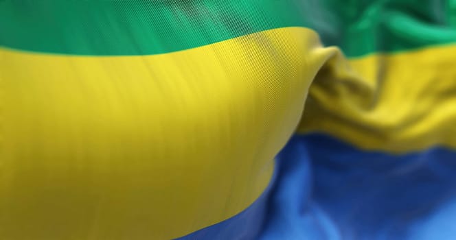 Close-up view of the Gabon national flag waving in the wind. The Gabonese Republic is a Central African Country. Fabric textured background. Selective focus