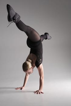Ballet dancer woman black dress on gray background, Ballerina posing and showing her flexibility on gray background in studio.