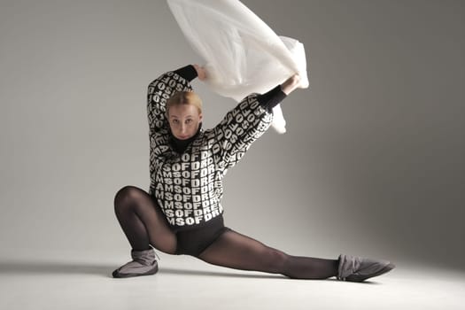 Ballerina Dancing with Silk Fabric, Modern Ballet Dancer with Waving white fabric, Gray Background. With text on sweater DREAMS OF.