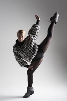 Ballet dancer woman black dress on gray background, Ballerina posing and showing her flexibility on gray background in studio. With text on sweater DREAMS OF.