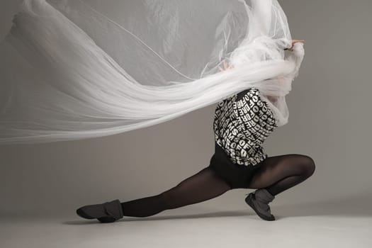 Ballerina Dancing with Silk Fabric, Modern Ballet Dancer with Waving white fabric, Gray Background. With text on sweater DREAMS OF.