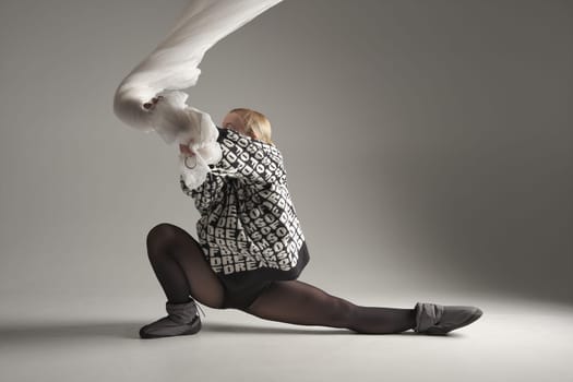 Ballerina Dancing with Silk Fabric, Modern Ballet Dancer with Waving white fabric, Gray Background. With text on sweater DREAMS OF.