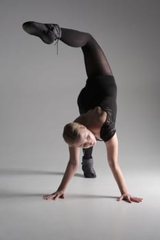 Ballet dancer woman black dress on gray background, Ballerina posing and showing her flexibility on gray background in studio.