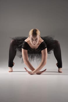 Ballerina Dancing with tutu Modern Ballet Dancer in dancer tutu, Gray Background. Dancer in Black clothes showing her flexibility posing on gray background in studio.