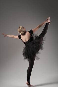 Ballerina Dancing with tutu Modern Ballet Dancer in dancer tutu, Gray Background. Dancer in Black clothes showing her flexibility posing on gray background in studio.