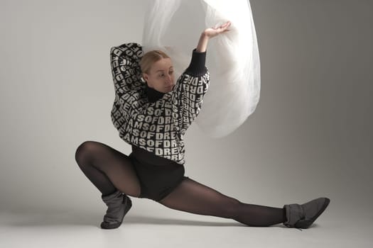 Ballerina Dancing with Silk Fabric, Modern Ballet Dancer with Waving white fabric, Gray Background. With text on sweater DREAMS OF.