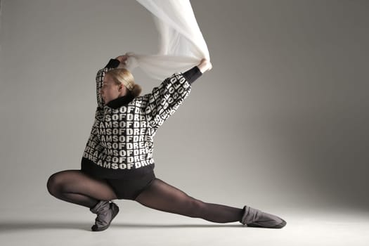 Ballerina Dancing with Silk Fabric, Modern Ballet Dancer with Waving white fabric, Gray Background. With text on sweater DREAMS OF.