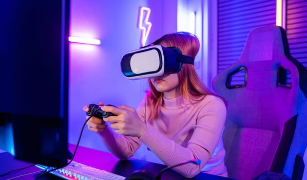 Gamer in VR headset glasses exploring metaverse play video game online with joystick on computer neon lights, Excited woman virtual playing gamepad controller she very determined at home