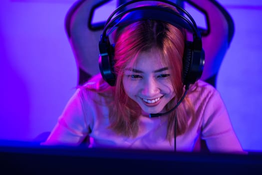 Young woman wearing gaming headphones intend to do playing live stream games online at home, Happy Gamer endeavor plays online video games tournament with computer neon lights