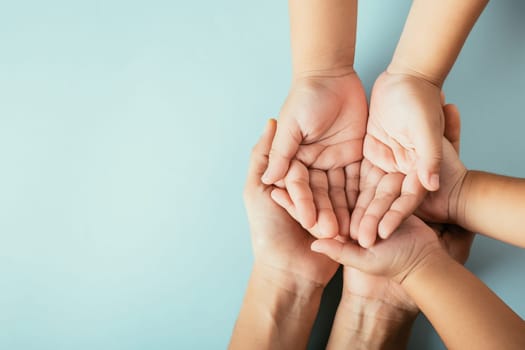 Top view parents and little kid holding empty hands together studio shot isolated on blue background, family home, hands children on adult mother hand, help support, parents family day concept
