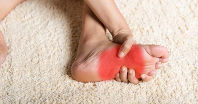 Foot pain, Asian woman feeling pain in her foot at home, female suffering from feet ache use hand massage relax muscle from soles in home interior, Healthcare problems and podiatry medical concept