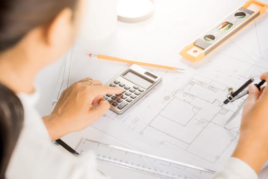 Architectural project workplace. Engineer sketching construction project, Architect drawing with divider compass on house plan blueprint paper for repair tools on table desk at architecture office