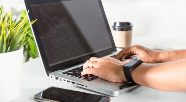Programmer woman writing program HTML code sitting at workplace in office, IT software developer hands typing data coding programming with laptop computer, IT start up concept, Web application design