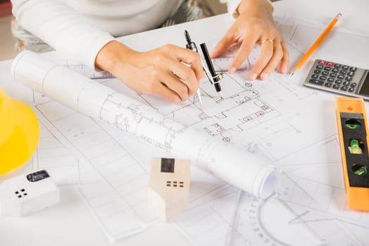 Architectural project workplace. Architect drawing with divider compass on house plan blueprint paper for repair tools on table desk at architecture office, Engineer sketching construction project