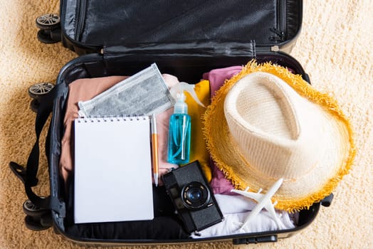 Open suitcase with traveler belongings clothes and accessories of things ready packing to be taken on summer holiday, Travel vacation luggage preparations concept, top view