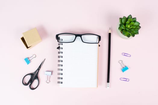 Empty notebook with a pen, eyeglasses and a cactus on a pastel colored desk, brainstorming for new ideas, writing a message, home office workplace