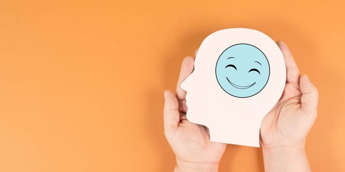 Holding a head with a happy smiling face, mental health concept, positive mindset, support and evaluation symbol