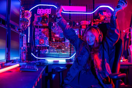 Winning. Happy Gamer young plays online video games computer she raises hands to wins tournament, young woman in gaming headphones playing video game online at home feel excited, E-Sport concept